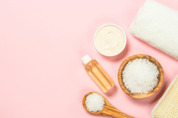 Spa flat lay background with sea salt and cosmetic oil on pink.