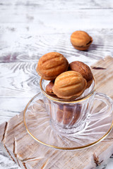 Walnut shaped cookies with caramel in a glass cup on the white table. Special skillet in the background