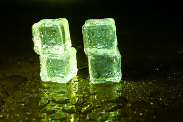 Green ice cubes on black table background.