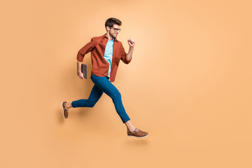 Full length body size view of his he nice attractive cheerful content successful guy leader jumping in air carrying laptop running fast hurry-up meeting isolated over beige color pastel background