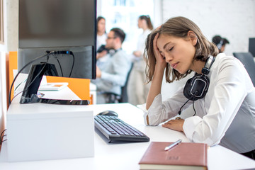 Young attractive woman operator with headset over neck suffering from headache