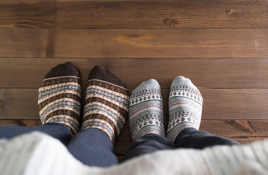 couple with woolen socks sitting on wooden floor, winter cosy scene