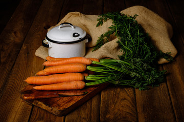 Still life of freshly harvested carrots on cutting board with knife and on old wooden background