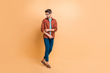 Fototapeta na wymiar Full length body size view of his he nice attractive fashionable content brunet guy partner hipster walking fixing sleeve isolated over beige color pastel background