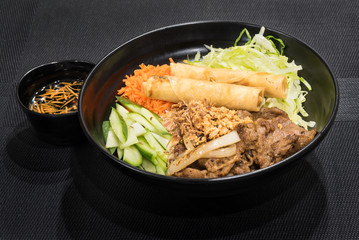 Rice noodles with grilled meat and spring roll, a popular Vietnamese cold rice vermicelli. Vietnamese cuisine.