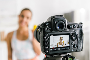 selective focus of digital camera with happy woman holding apple on screen