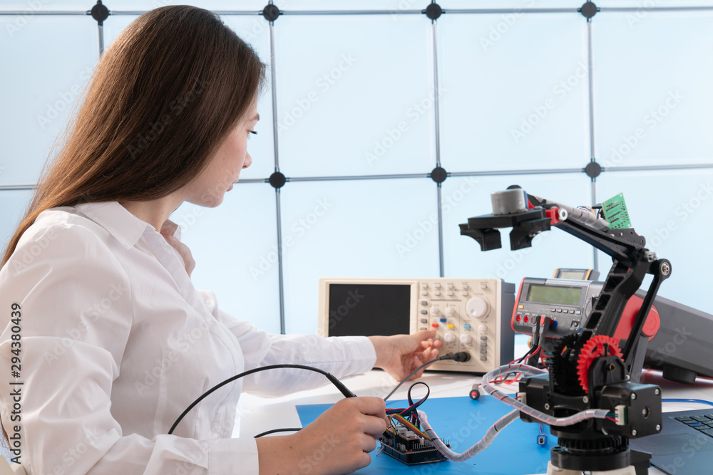 Poster a young woman writes an algorithm for the robot arm. science research laboratory for robotic arm mod