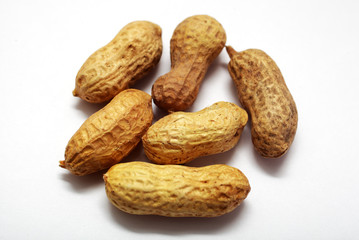 a pile of unpeeled peanuts on a white background
