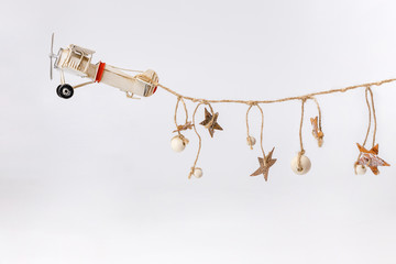 Miniature toy retro airplane with handmade garland of rope and wooden stars on white background....