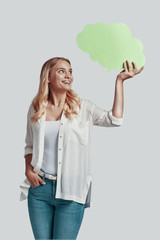 Beautiful young woman looking away and smiling while standing against grey background