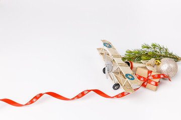 Miniature toy retro airplane with little gift, fir tree, ball and ribbon on white background. Metal model.