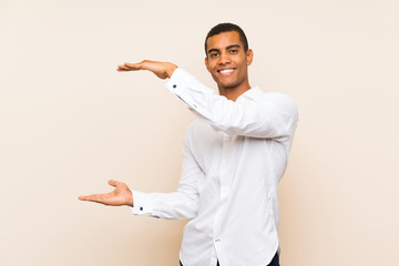 Young handsome brunette man over isolated background holding copyspace to insert an ad