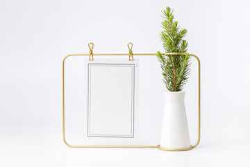 Little fir tree in ceramic vase and golden frame on white background. Christmas card - toys, garlands and wooden thinks.