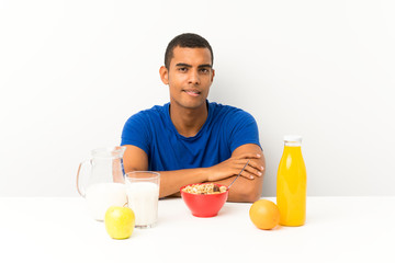 Young man having breakfast in a table having doubts and with confuse face expression