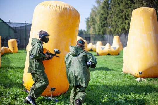 Paintball players on the training ground. The game of shooting paint. Playground with inflatable obstacles. Combat strategy in game military action.