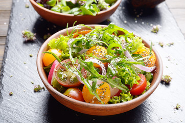 Vegetable salad of lettuce, cherry tomatoes, radish, cucumber, onion and basil on slate tray