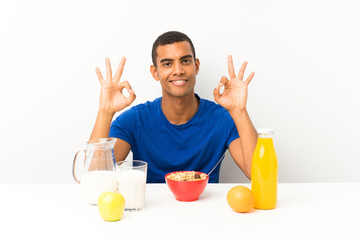 Young man having breakfast in a table showing an ok sign with fingers