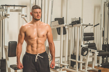 Fototapeta na wymiar Fitness instructor in the sport room background. Male model with muscular fit and slim body. Sport concept