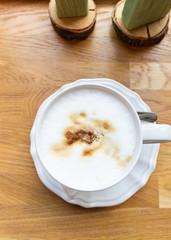 Top view of latte or cappuccino in a white cup on wooden table in cafe.