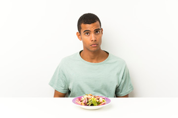 Young handsome man with salad in a table sad