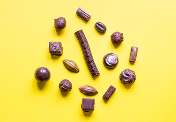 Delicious chocolate candies on yellow paper background.
