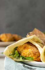 Tortilla wraps with chicken or turkey cutlets, arugula and sour cream sauce on a ceramic plate.