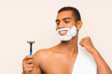 Young handsome man shaving his beard over isolated background celebrating a victory