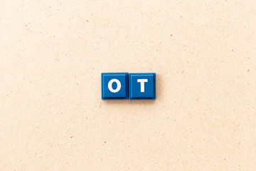 Tile letter in word ot (abbreviation for overtime) on wood background