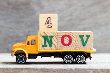 Truck hold letter block in word 4nov on wood background (Concept for date 4 month November)