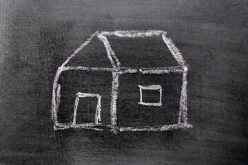 White color chalk hand drawing in home shape on blackboard background