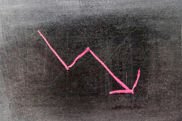 Red chalk drawing in down trend arrow shape on black board background