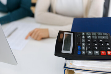 Calculator and binders with papers are waiting to be processed by business woman or bookkeeper...