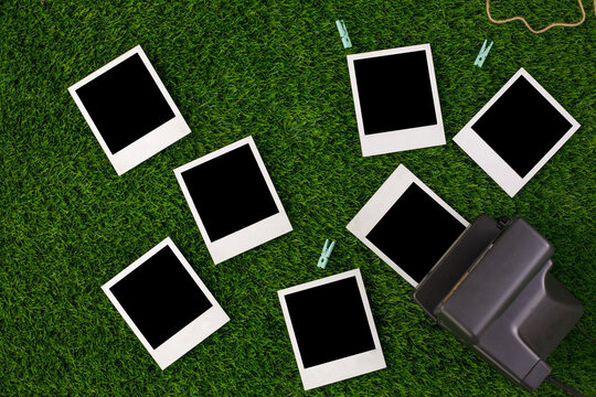 Instant photo frames and a camera on a background of lawn grass. Concept of preservation of memories. Flat lay.