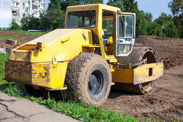 Bulldozer at a construction site. Heavy machinery performs construction work. A bulldozer levels the ground. The car is diesel powered.