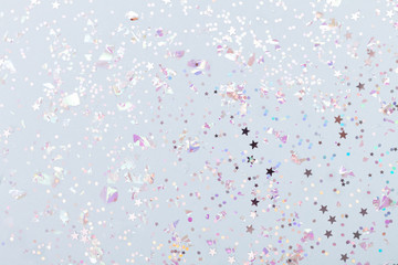 Christmas festive banner background: confetti with sparkling glitter and stars on blue background. Festive and bright. Top view, flat lay.