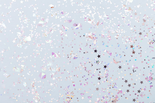 Christmas festive banner background: confetti with sparkling glitter and stars on blue background. Festive and bright. Top view, flat lay.