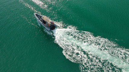 Aerial top view luxury inflatable rib speed boat cruising in mediterranean emerald bay with crystal clear sea