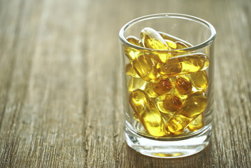 Group of fish oil carry on glass lay on wood table
