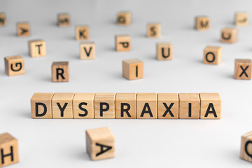 Dyspraxia - word from wooden blocks with letters, difficulties with physical movement and memory, dyspraxia concept, random letters around, white  background