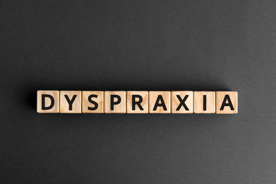Dyspraxia - word from wooden blocks with letters, difficulties with physical movement and memory, dyspraxia concept, gray   background
