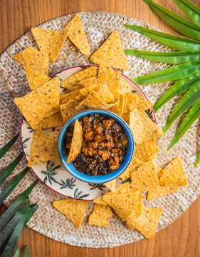 Raci&oacute;n de nachos con frijoles en un plato blanco