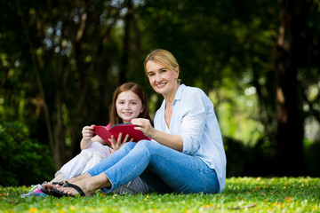 Fototapeta premium Mother and son are reading a book and smile at the park