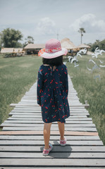 Back view of little girl walking on the wooden bridge 
