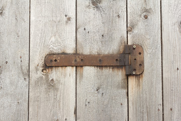 Fragment of closed old wooden gate with rusty hinges