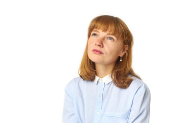 Headshot of redheaded girl with freckles and bang hairstyle dressed in blue shirt and looking upwards as if dreaming about something pleasant
