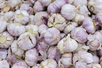 Ripe white garlic whole in a dry peel background. Spicy spice fresh garlic, healthy vegetable garlic top view. A large pile of garlic on a box in a supermarket