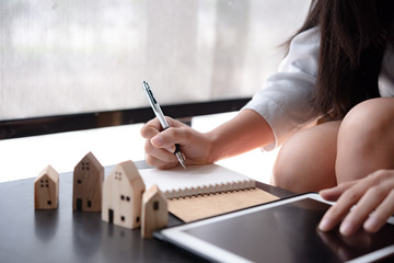 wooden toy house medel with Woman Plan to sign a contract to buy a house, Real estate concept.