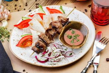 pork kebabs on a plate with sauce on a wooden table