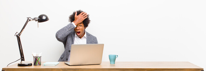 young black businessman raising palm to forehead thinking oops, after making a stupid mistake or...