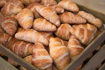 Croissants in an open wooden box. Freshly baked croissants in wooden crate, box, top view. Tasty bakery for brunch. Private bakery background. Brunch background.